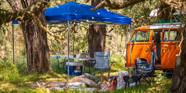 Camping set up with gazebo, chairs and table.