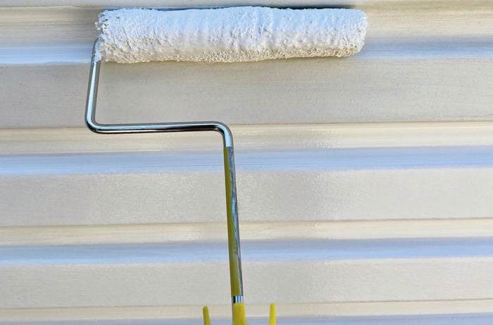 Roller with paint on grooves of garage door.