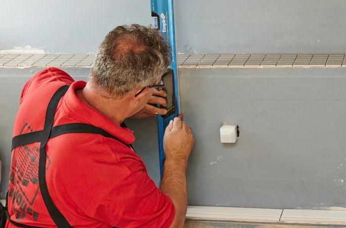 A spirit level being used to mark a wall for the application of tiles