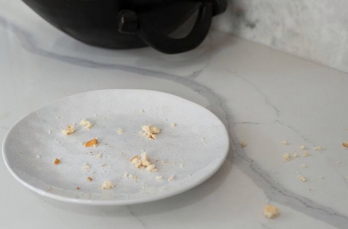 Bread crumbs are placed on a plate on a marble countertop