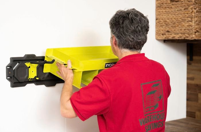 A Bunnings Team Member is mounting a Ryobi LINK storage shelf onto the installed wall rail system.