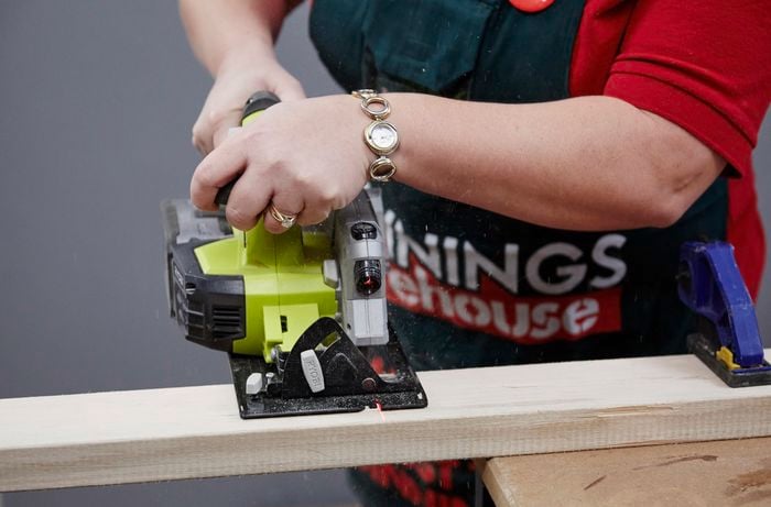 Person using circular saw to cut piece of timber.
