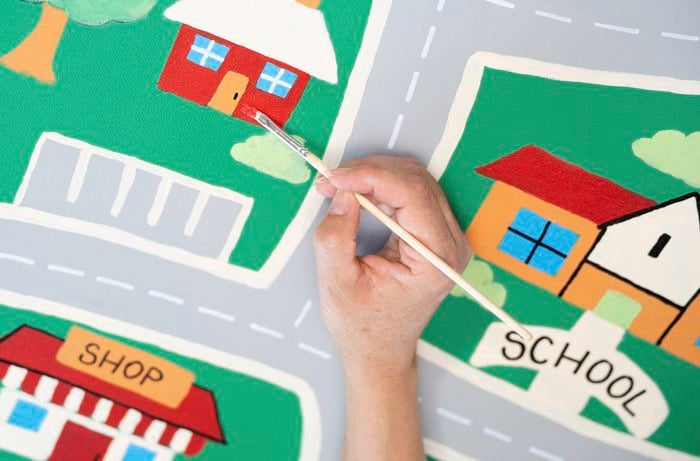 A person is using a paintbrush to fill in key features between the lines to complete the artwork.