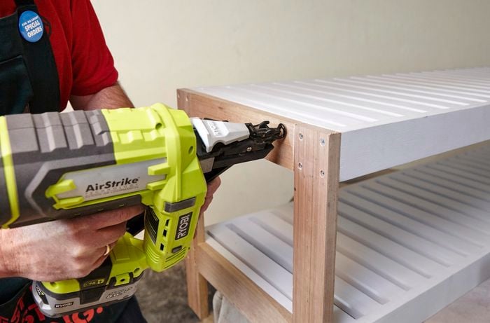 Person nailing shelves to frame