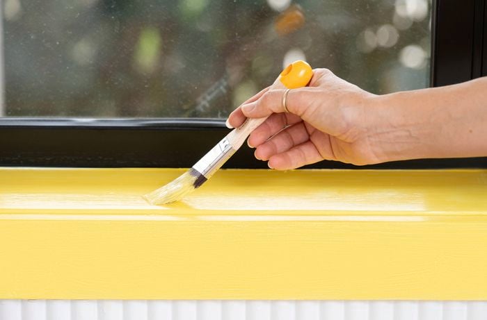 A person is applying yellow paint to a 