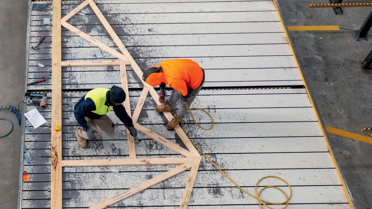 Two men in hi-vis work on Bunnings Trade frame and truss at a plant