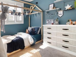 Child's bedroom with bed, toys and chest of drawers covered with wallpaper