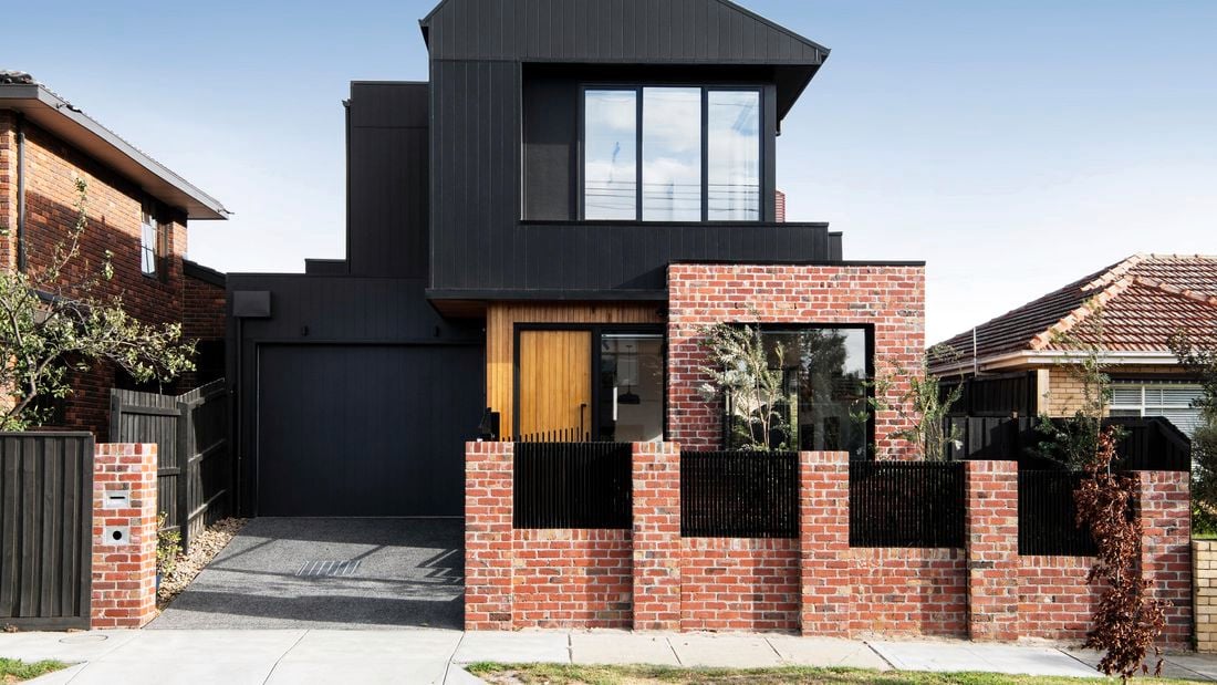 Modern two-story house with a black timber and exposed brick exterior