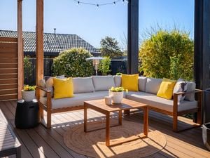Timber outdoor setting on wooden decking with trees around the decking.
