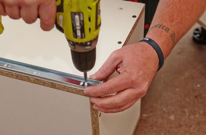 Person drilling drawer runner to the outside of drawer.