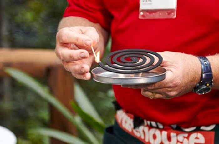 A Bunnings team member lighting a mosquito coil