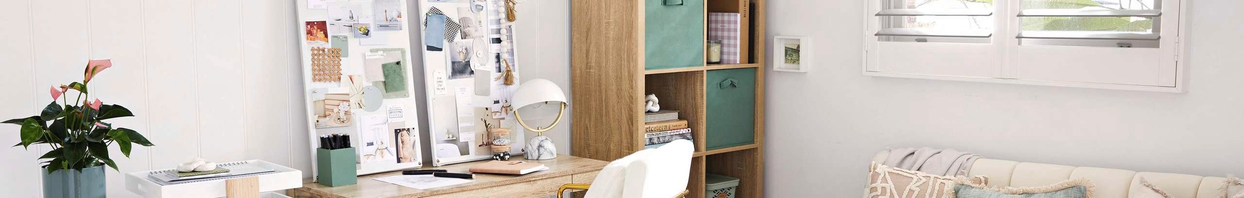Home office with neutral tones, timber desk, white and gold chair, white timber panelled wall and a cream couch with feature cushions