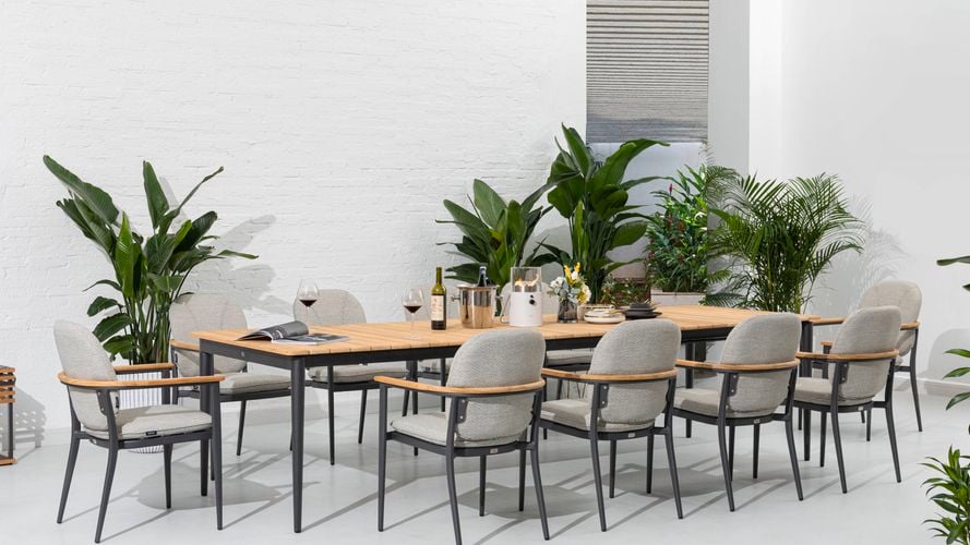 An outdoor dining setting with ten aluminium chairs and a teak extendable table