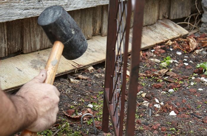 A Bunnings team member hammering a garden archway into the ground