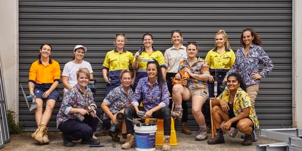 13 trade ladies sitting in front of a garage door