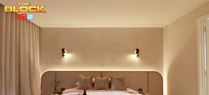 Contemporary bedroom featuring soft pink bedding, a curved upholstered bedhead, neutral walls and wall-mounted bedside lights.