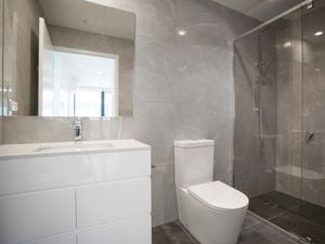 Grey Marble-walled bathroom with a sink, toilet and shower.