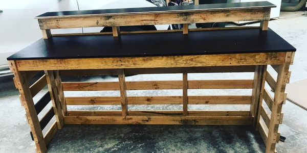 A DIY timber bar with black benchtops in a garage