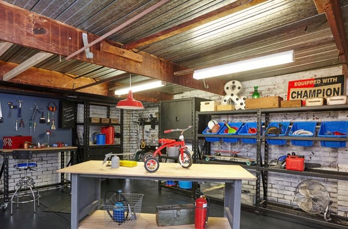 Organised garage with garage shelves full of assorted items and workbench in the middle of the room.