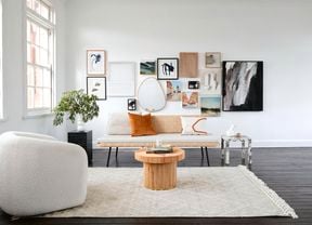 Lounge room with carpet, single chair, couch, indoor plant, decor n walls and central and side tables.