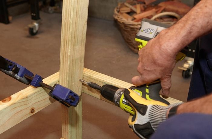 Person drilling wooden garden bench together.