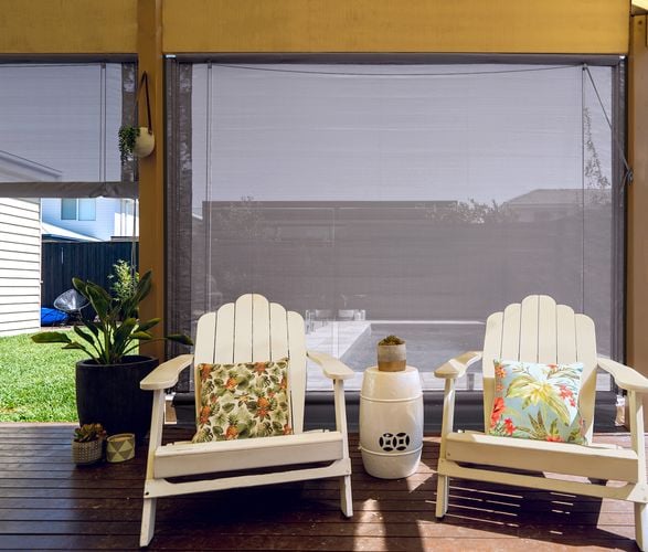 Covered timber decking area with white timber chairs