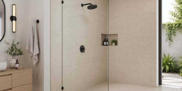 Close-up of a seamless glass shower with tiled walls, recessed niche, and view to an outdoor garden area.