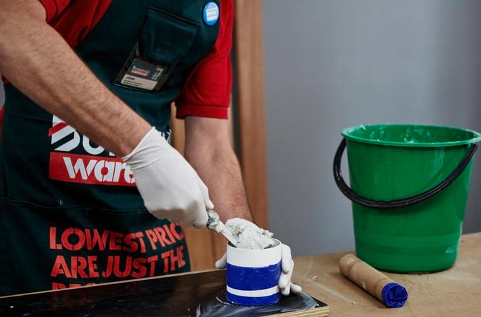 Close up of a Bunnings team member filling a small container with cement