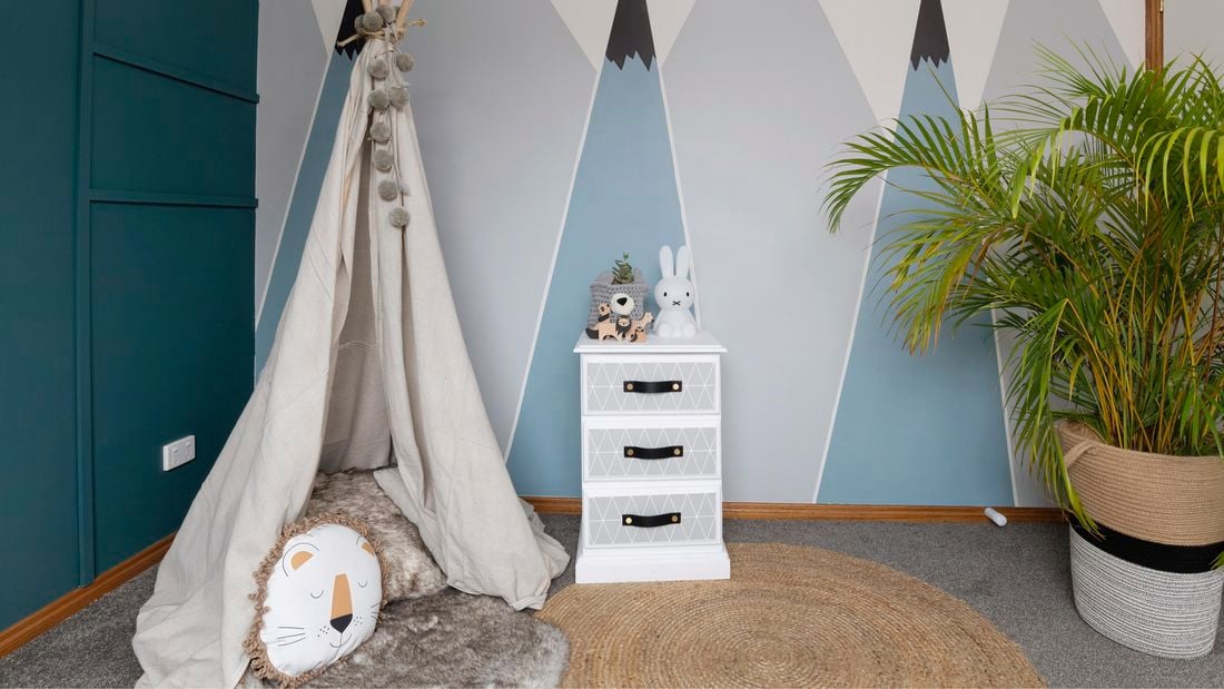 Kids bedroom with a homemade teepee tent in the corner and a three-drawer bedside table at the room's centre