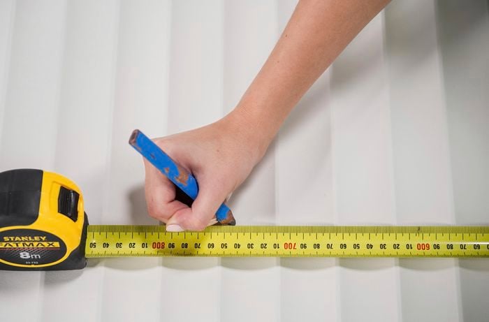 A scallop panel being measured and marked with a tape measure and pencil