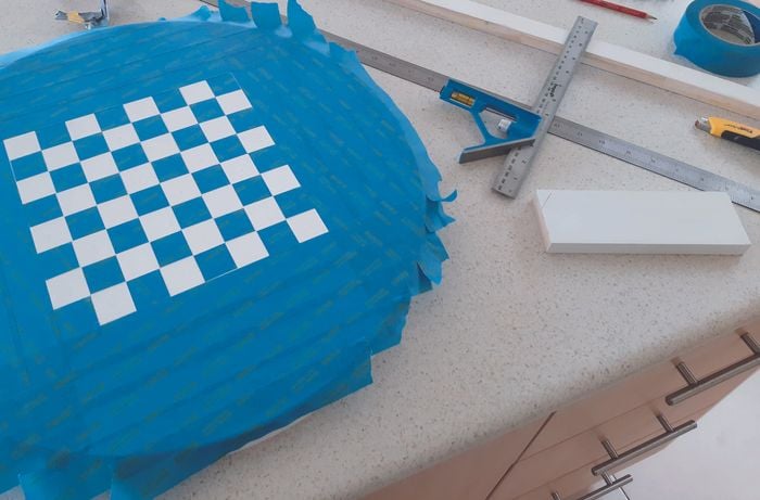 Blue masking tape is placed on table in a grid formation