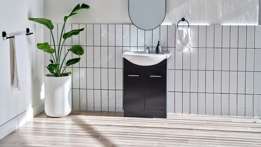 White tiled bathroom with black basin in shot 
