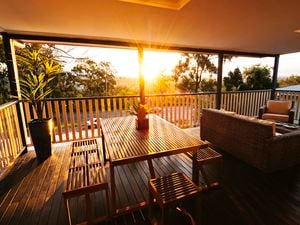 Deck with outdoor table and bench seat, with the sun streaming through.