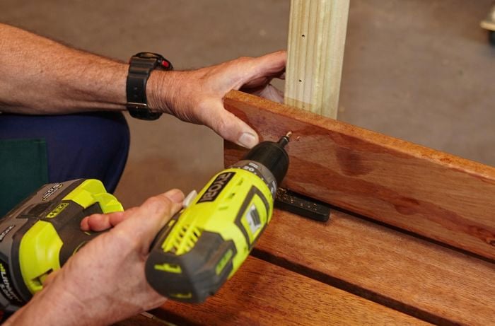 Person drilling DIY wooden garden bench together.