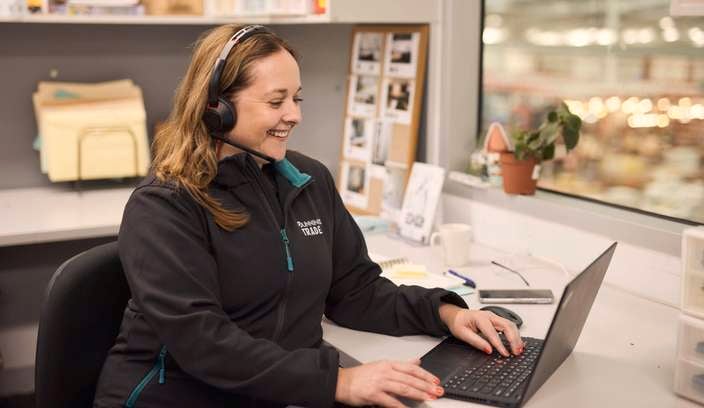 lady sitting at a desk with head phones on while using her laptop