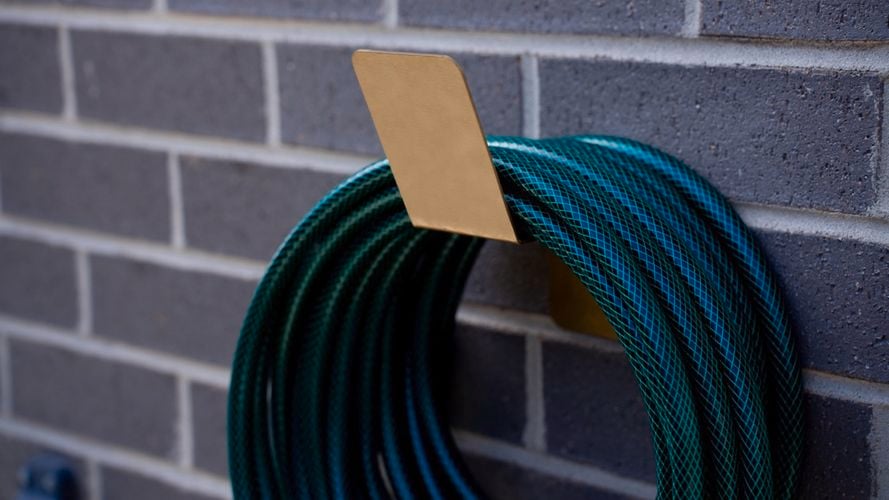 gold hose holder on wall 
