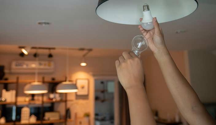 Hands changing light bulbs with new LED light bulb.