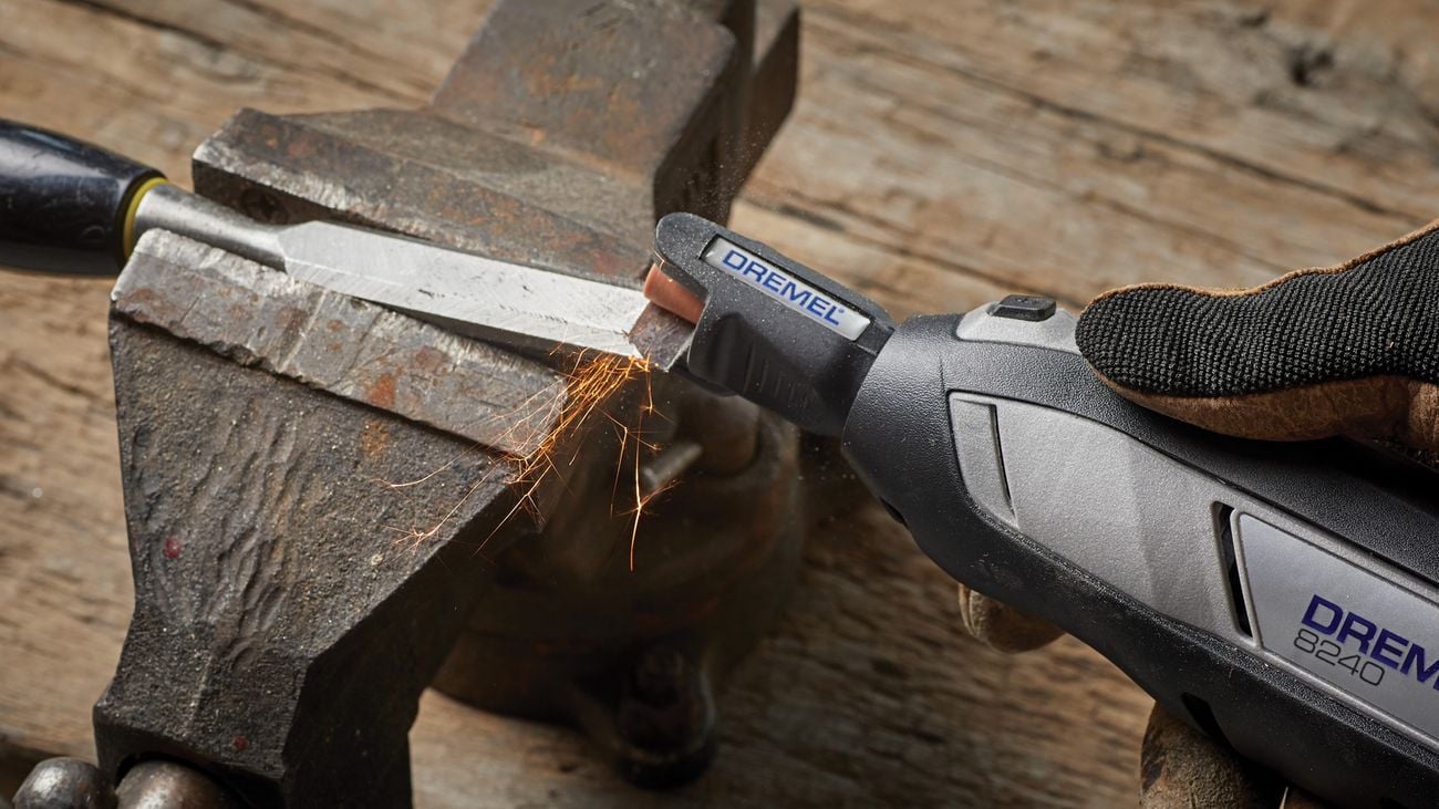 Dremel tool is sharpened using a sharpening tool on a wooden table