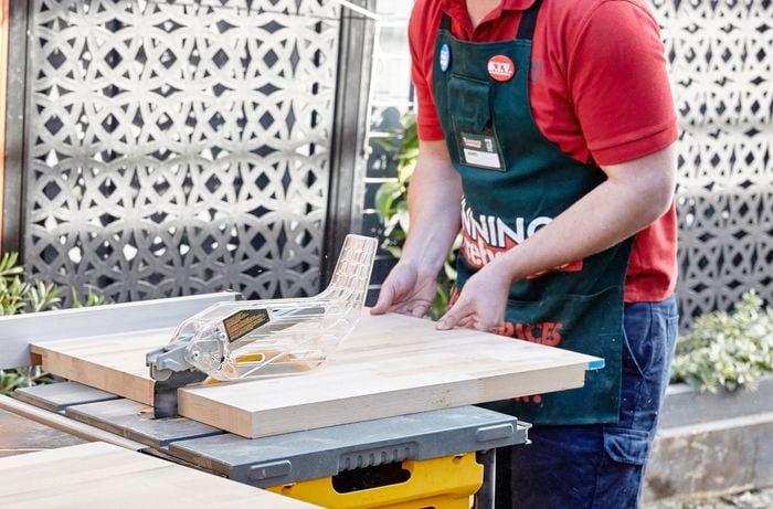 Person using circular saw to cut piece of timber to length.