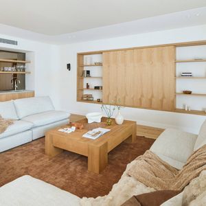 Contemporary living room featuring large neutral sofas, a timber coffee table and built-in timber shelving with concealed storage.