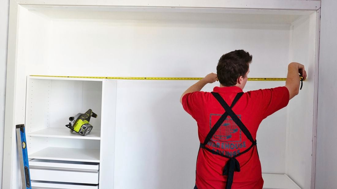 Person using measuring tape to measure inside of wardrobe.