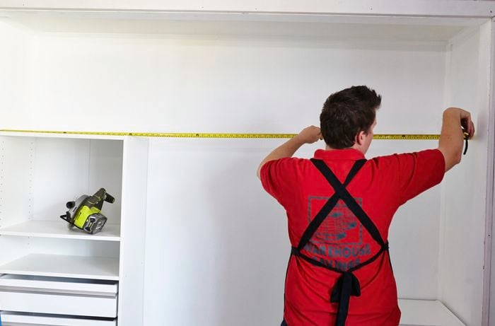Person using measuring tape to measure inside of wardrobe.
