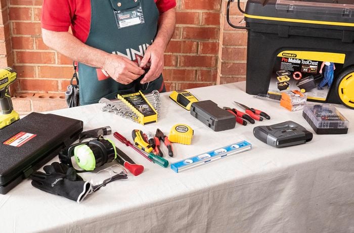 Person standing behind desk with lots of tools on it.