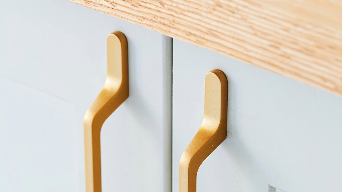 Close up of white cupboard doors with straight gold handles