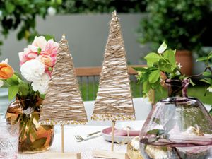 Cardboard Christmas trees on a decorated table with flowers in vases and tableware 