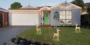Front of house with fairy lights, Christmas decorations in the window and lit up reindeers.