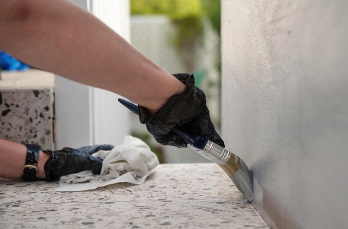A person painting the wall using a paint brush.