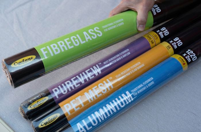 our rolls of flyscreen mesh labeled Fibreglass, Pureview, Pet Mesh, and Aluminium are displayed on a table to choose the right mesh based on specific requirements.