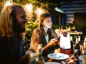 A man and a woman seated at a table in an outdoor dining setting, illuminated by an Energizer outdoor lantern