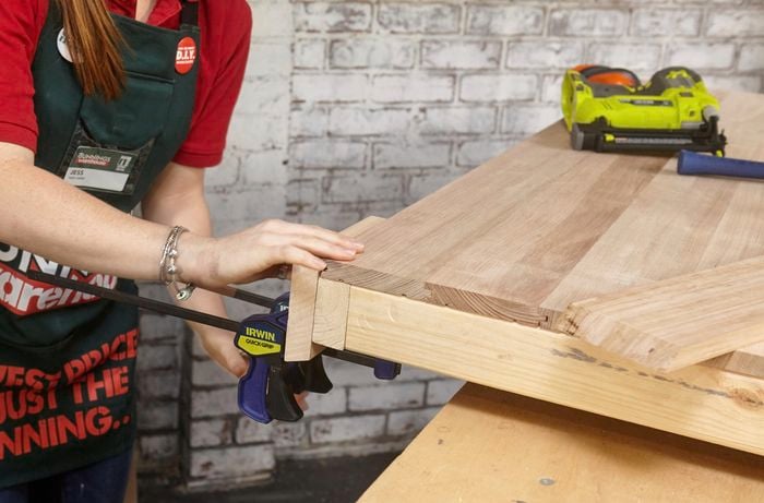 Person clamping together two pieces of timber.
